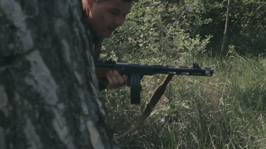 Two Soldiers In Uniforms And With Rifles Hiding Behind Tree And Fire At