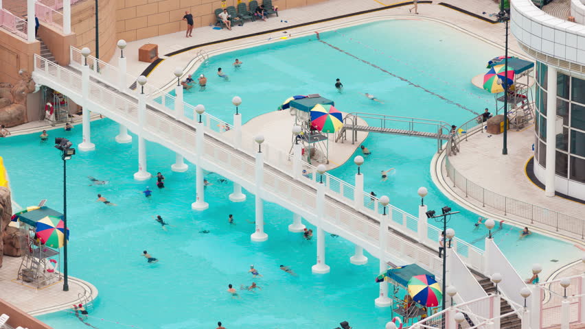 Aerial Helicopter Shot Of A Pool With Swimmers. Zooming In