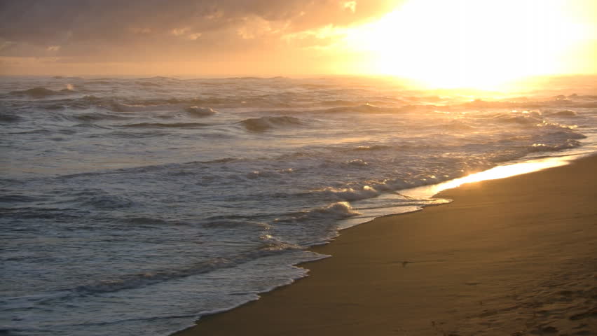 waves-gently-wash-up-onto-the-beach-then-recede-as-the-sun-starts-to