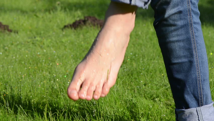 Bare Foot Woman With Tucked Jeans Walk On Early Morning Dewy Wet Meadow