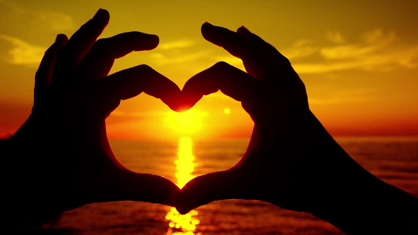 SLOW MOTION: Sunset Sun Shining Through Heart Shaped Hands Stock