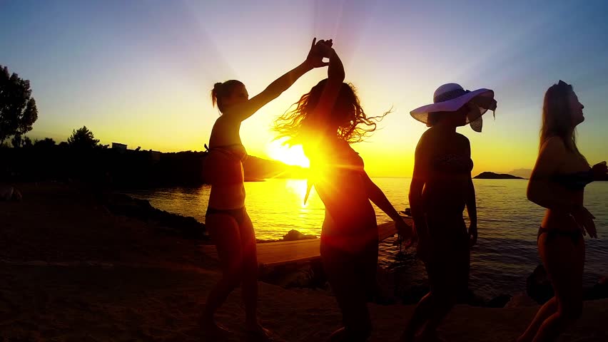 Group Of Happy Girls Dancing And Playing In Water At The Beach On