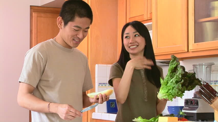 Happy Young Asian Couple Preparing Food In Kitchen Stock Footage Video