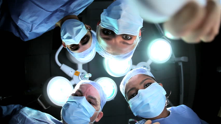 Head shoulders multi ethnic surgical team in gowns masks seen from below