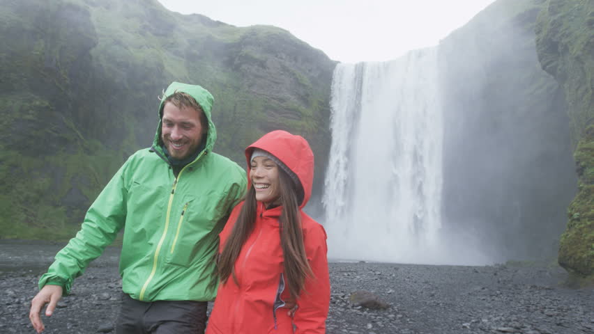 Iceland Tourists People Walking By Waterfall Skogafoss. Romantic Couple ...